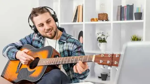 hombre-sonriente-tiro-medio-tocando-guitarra-_1_ Clases de guitarra online