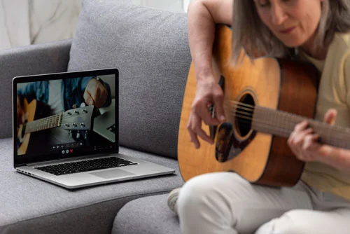 mujer-mayor-casa-sofa-laptop-lecciones-guitarra Clases de guitarra online