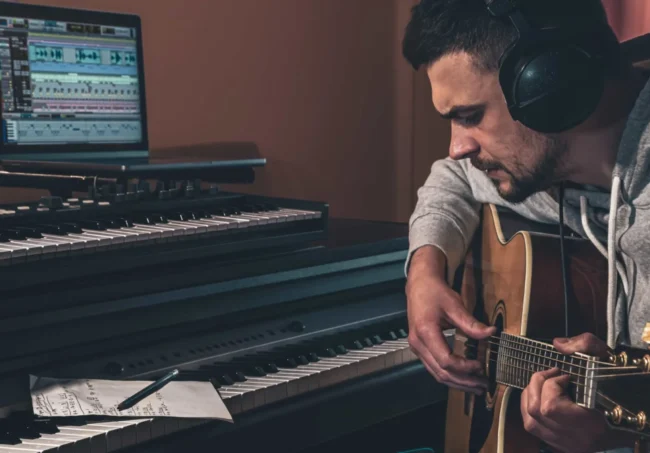 musico-masculino-toca-la-guitarra-en-casa-en-el-lugar-de-trabajo-cerca-de-la-computadora-_1_ Componer el tema principal es la base de toda composición.